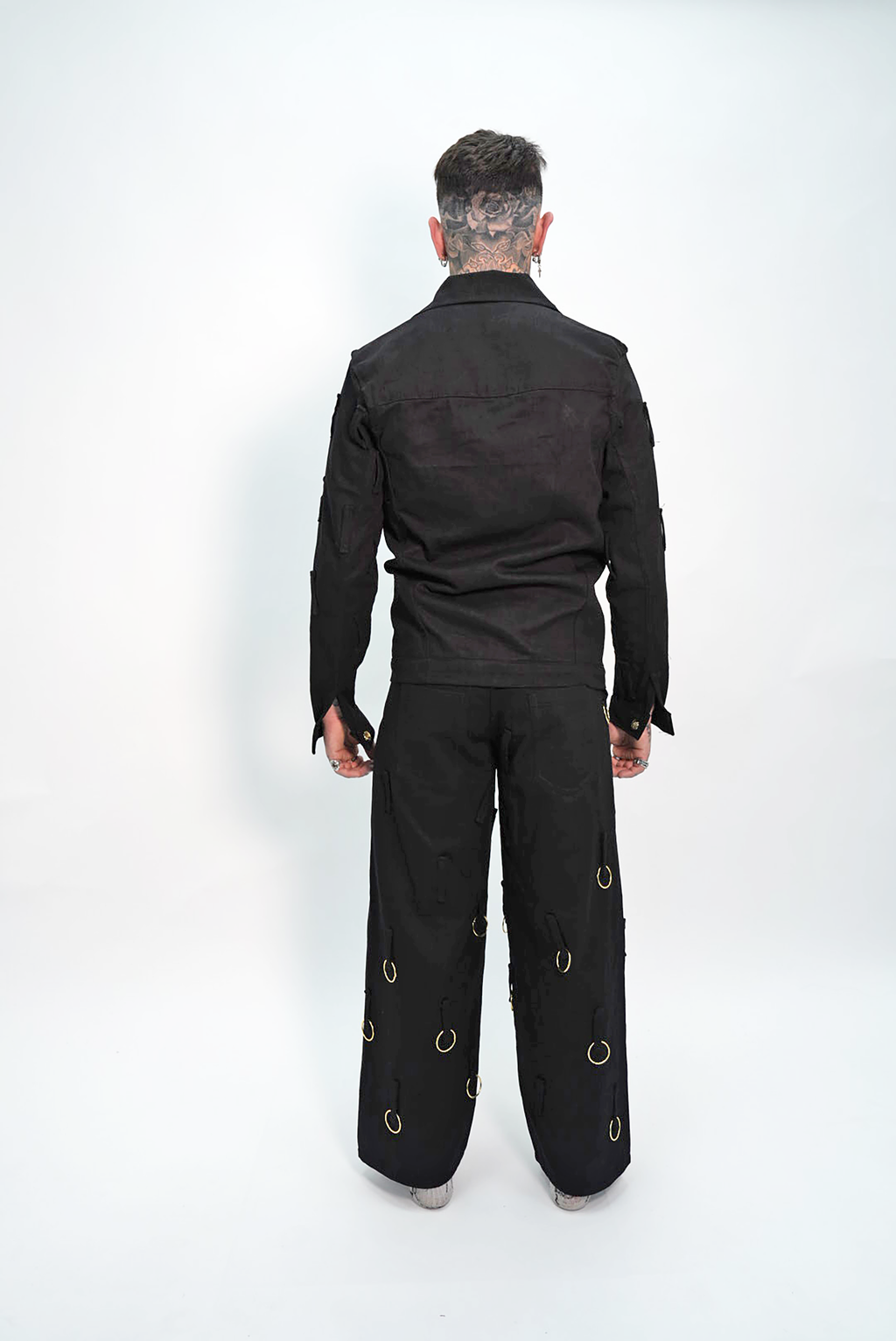 Person wearing a black outfit with unique design elements on a white background