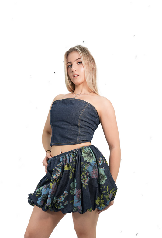 Woman wearing a strapless top and floral skirt with black knee-high boots on a white background